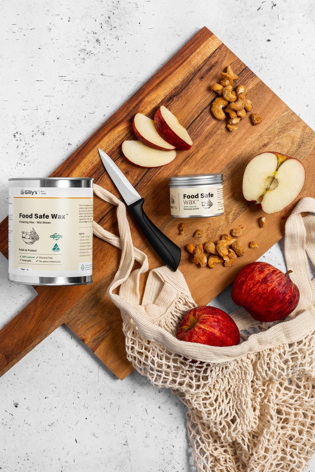 Food Safe Wax jars on wooden board with apples, cashews, knife, and reusable mesh bag