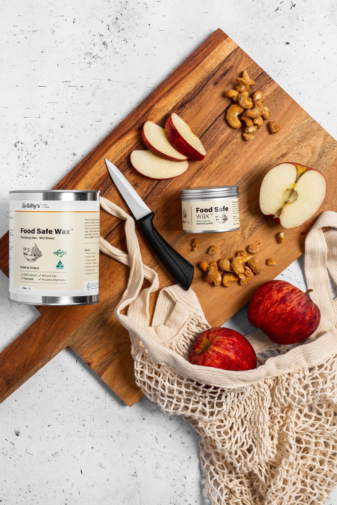 Food Safe Wax jars on wooden board with apples, cashews, knife, and reusable mesh bag