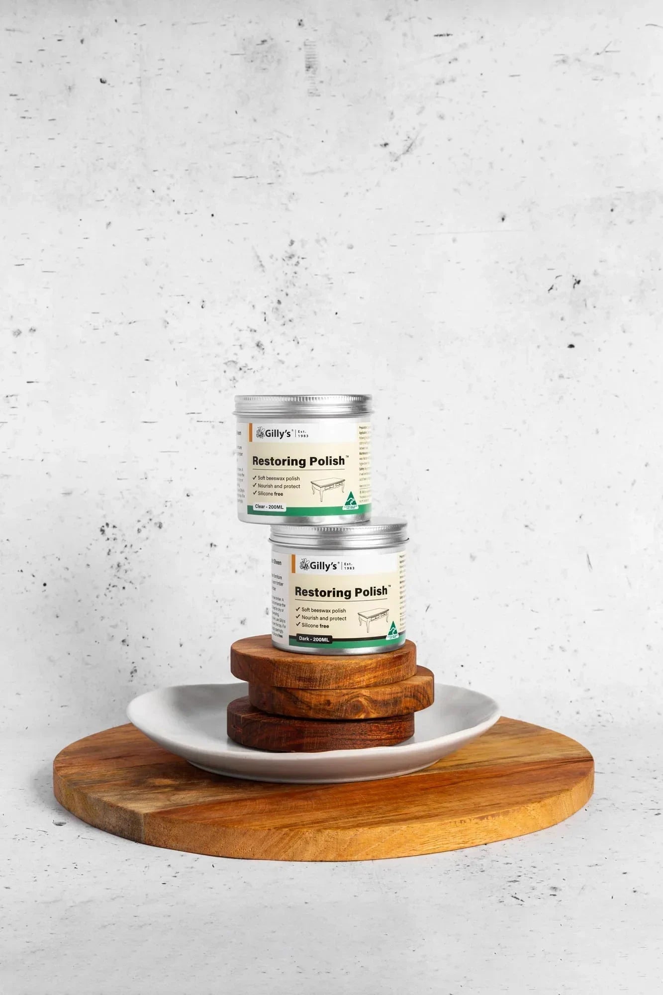 Gilly's Restoring Polish jars on stacked wooden boards and white plate, minimalist background