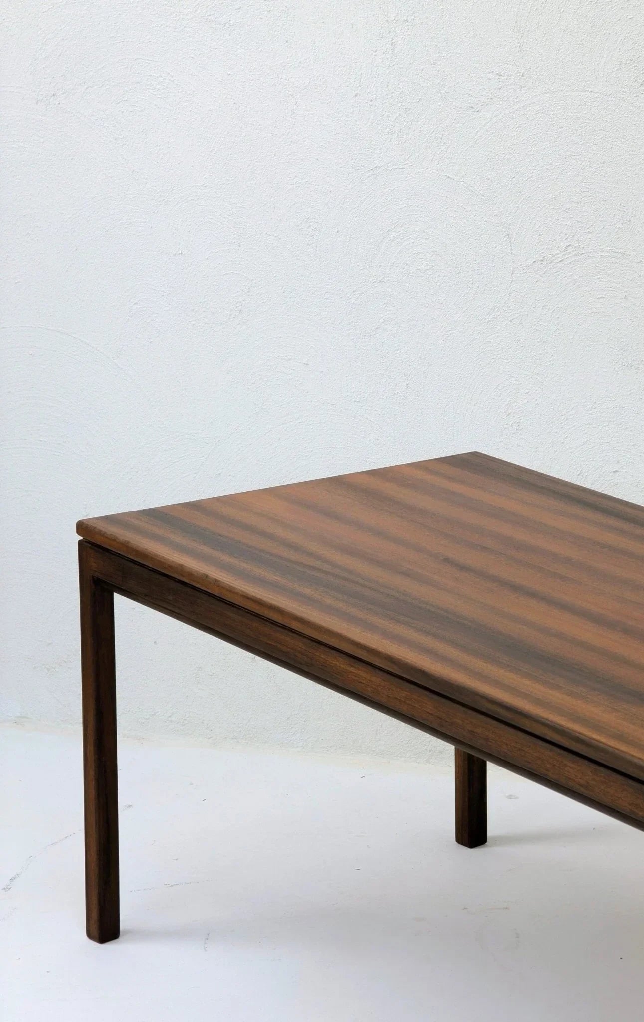 Mid-century modern wooden coffee table with striped veneer against a white textured wall
