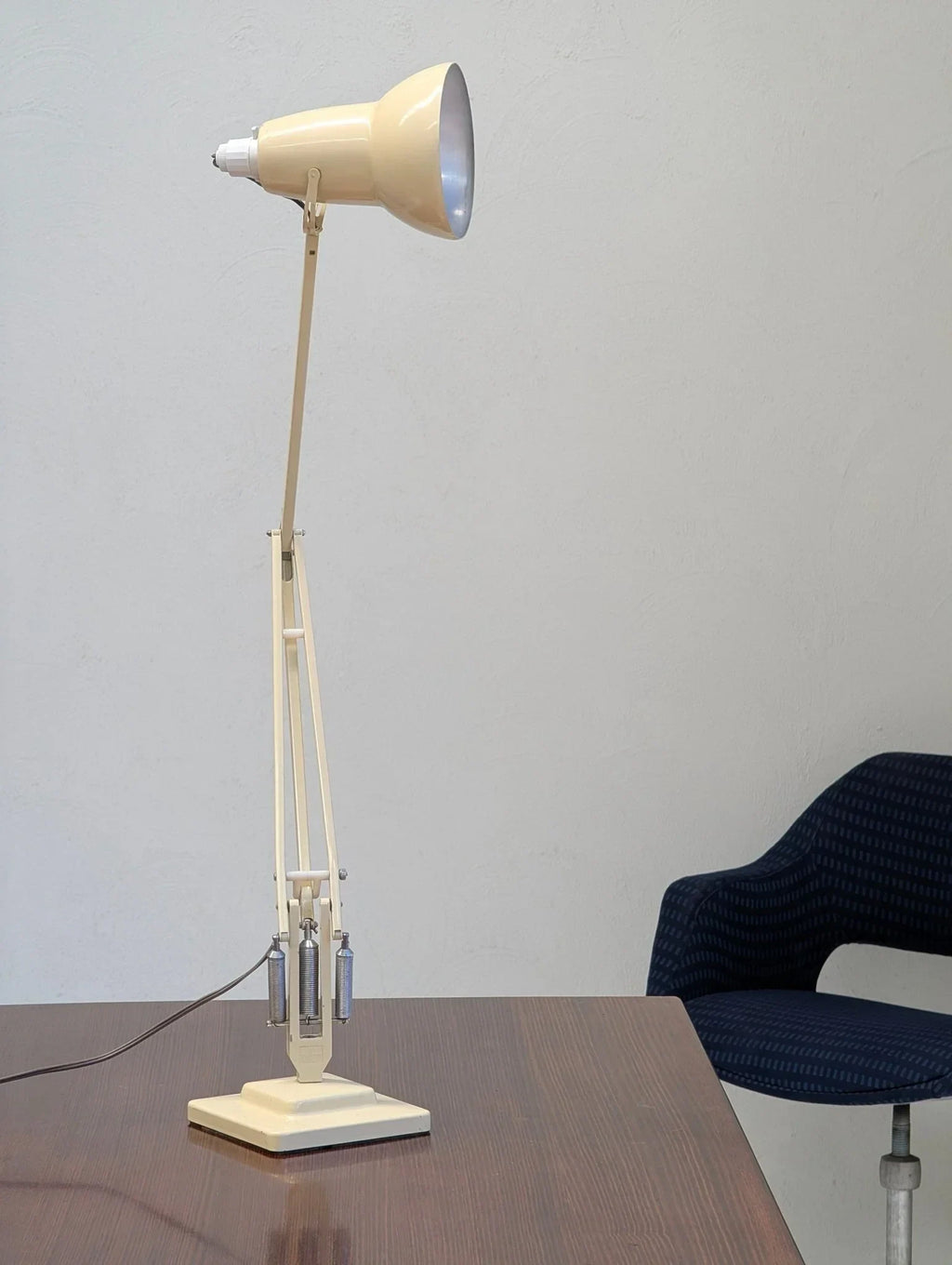 Vintage cream Herbert Terry Anglepoise desk lamp on wooden table near blue chair