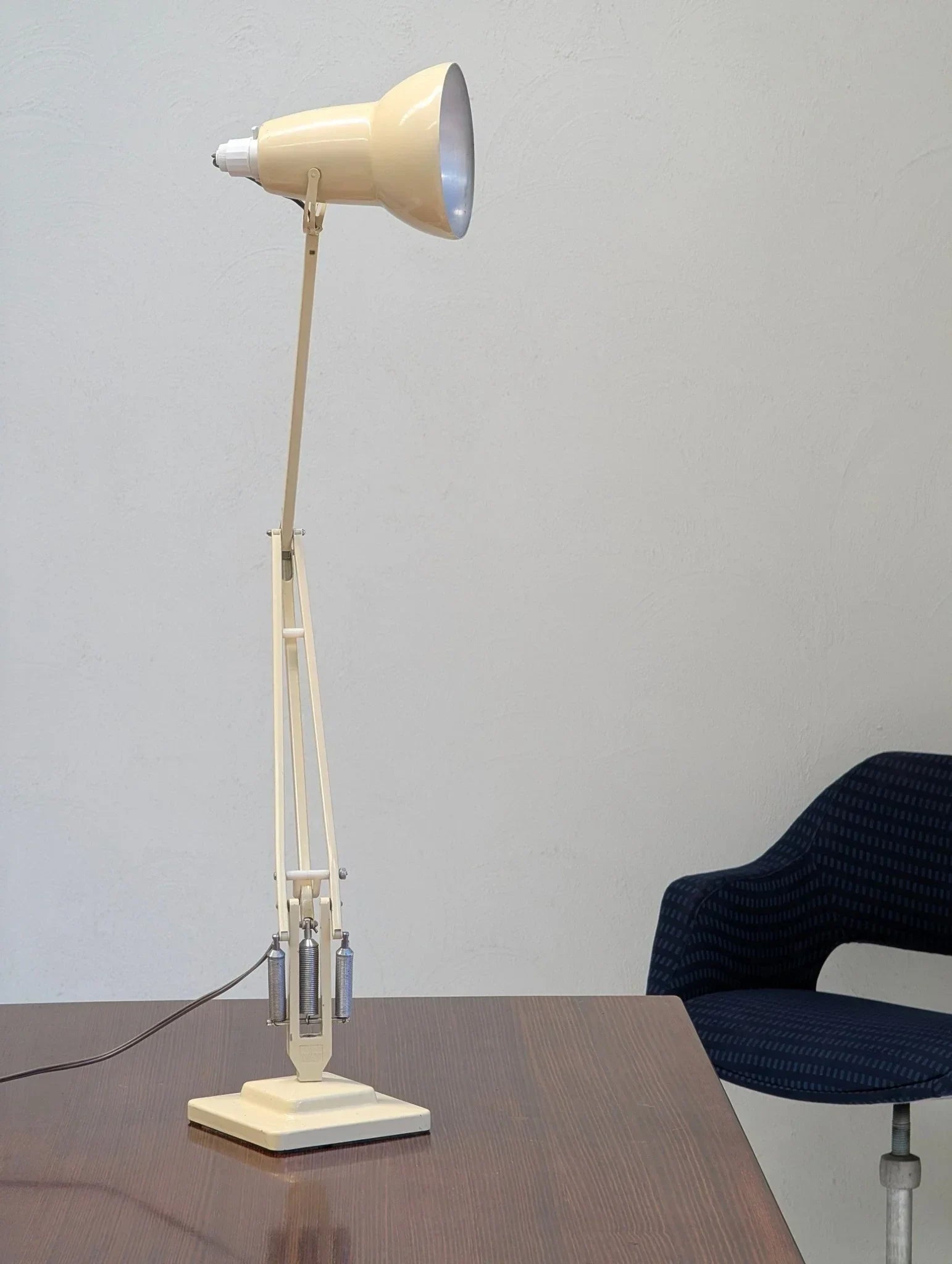 Vintage cream Herbert Terry Anglepoise desk lamp on wooden table near blue chair