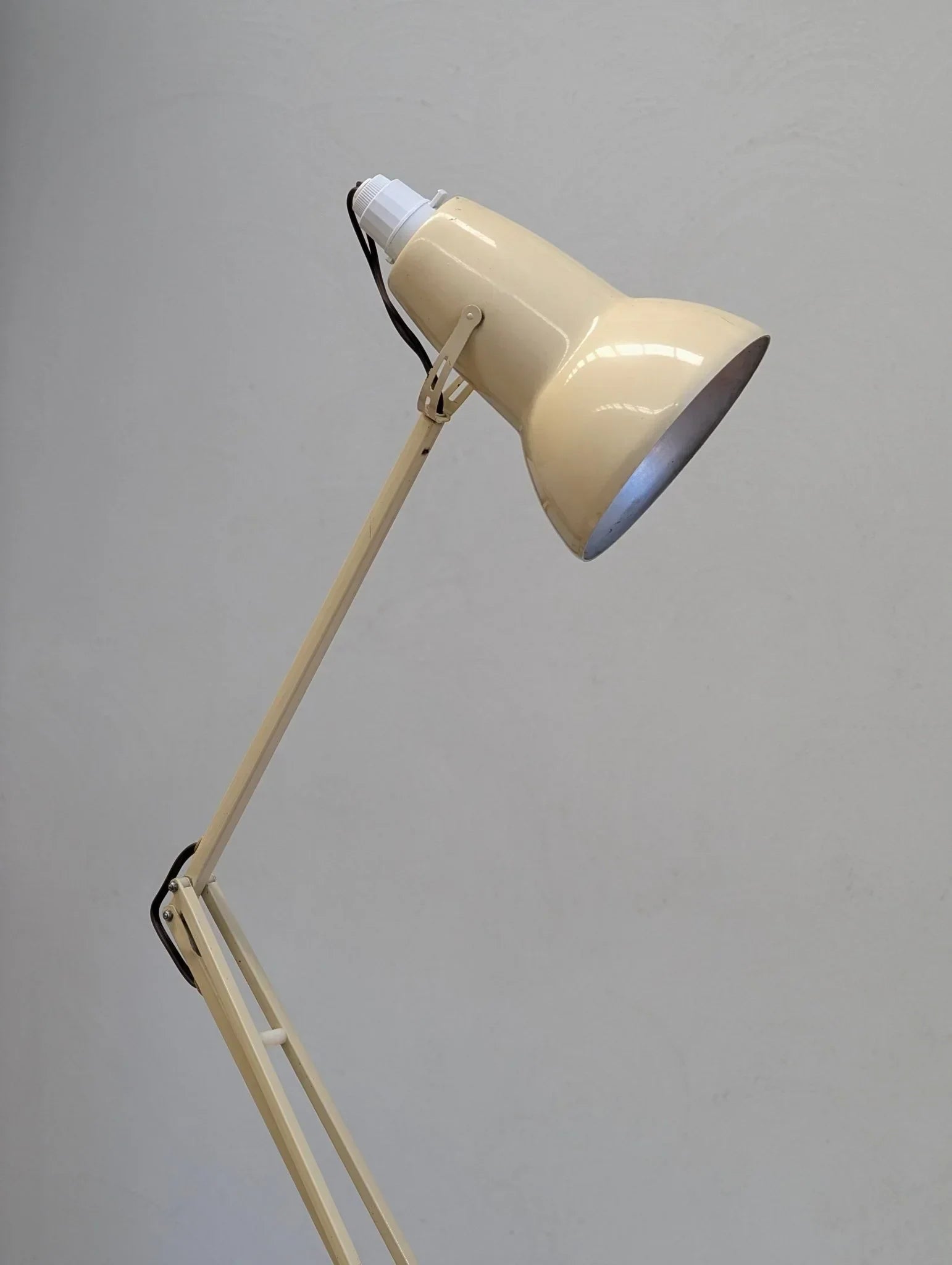 Vintage cream Anglepoise desk lamp with adjustable arm against a plain wall
