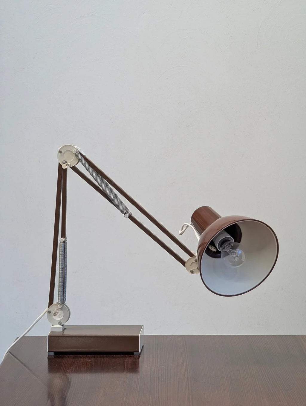 1970s brown Jac Jacobsen Luxo L-1 architects task lamp on a dark wooden desk