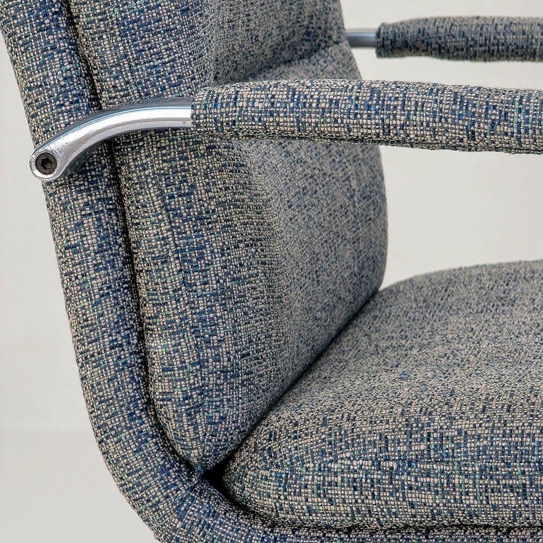 Close-up of 80s executive swivel armchair with textured blue wool upholstery and chrome armrest
