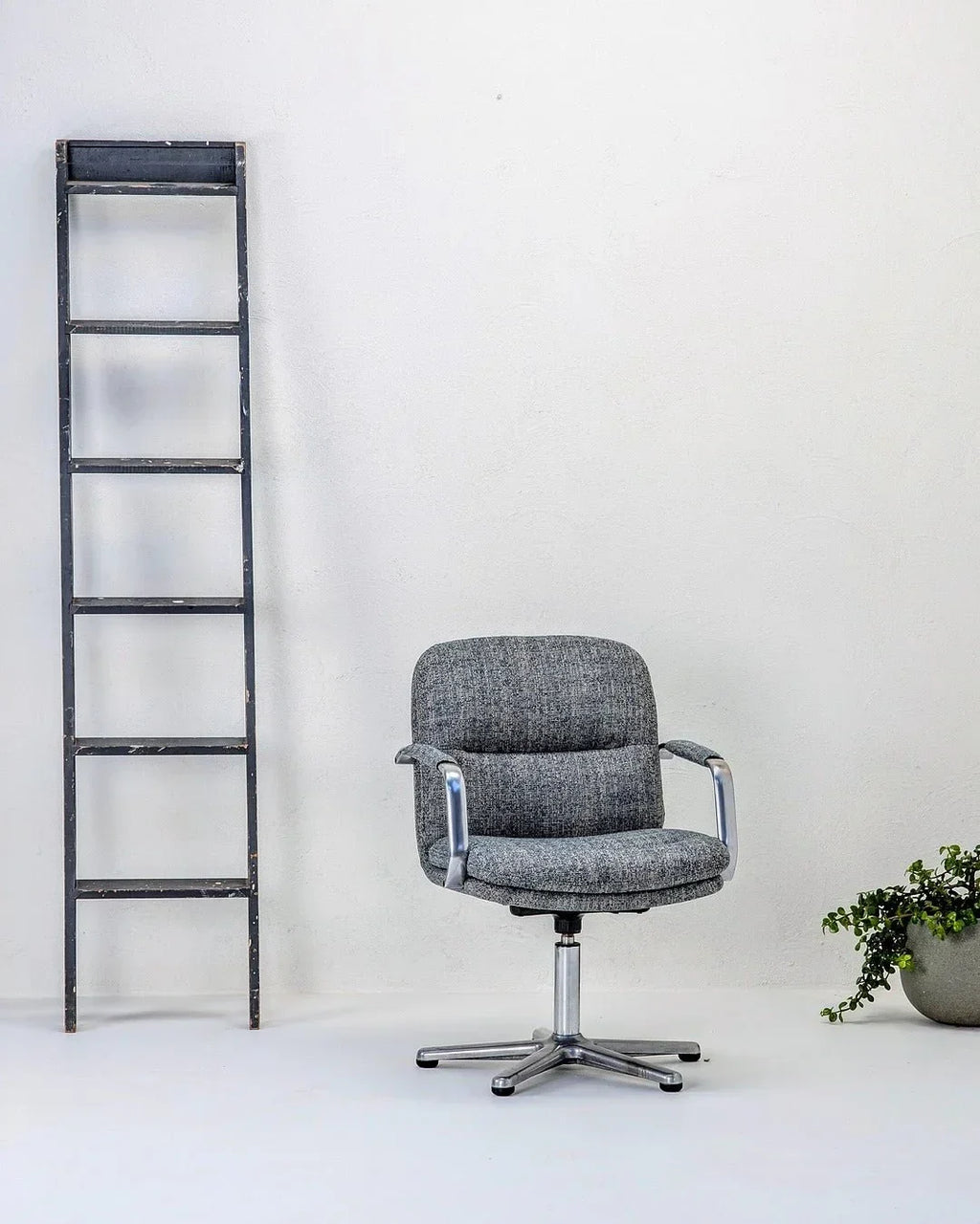80s executive swivel armchair in textured wool with metal base, beside ladder and plant