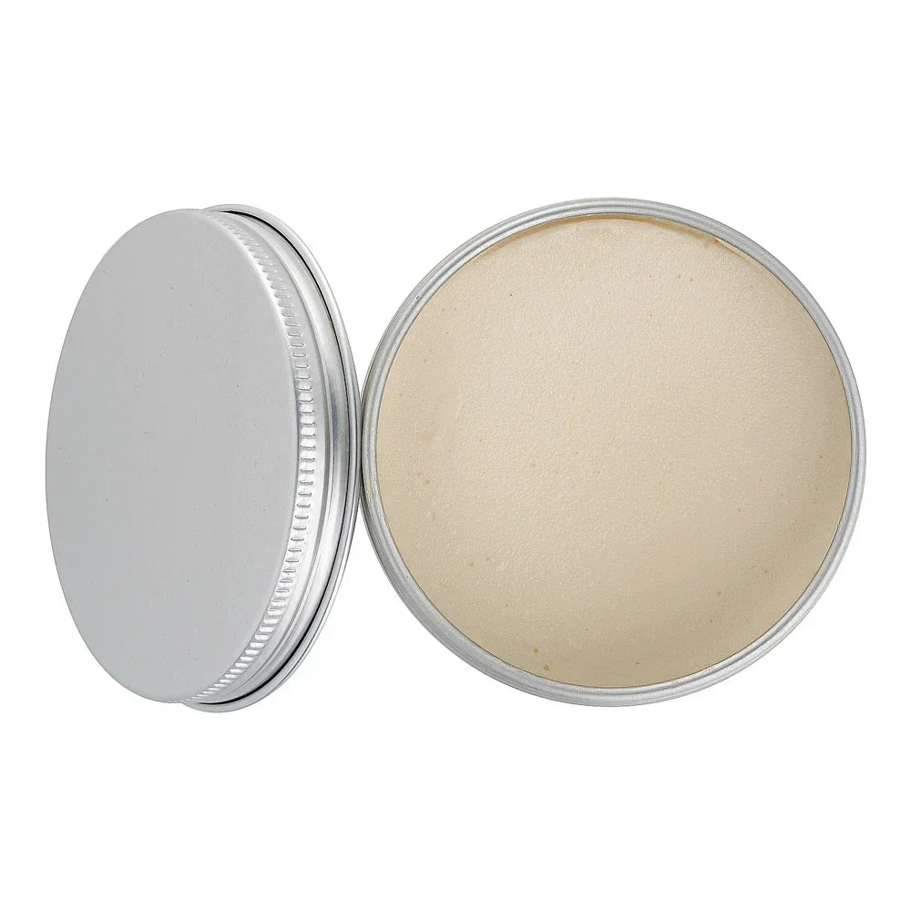 Open metal tin with beige solid balm, viewed from above, on white background