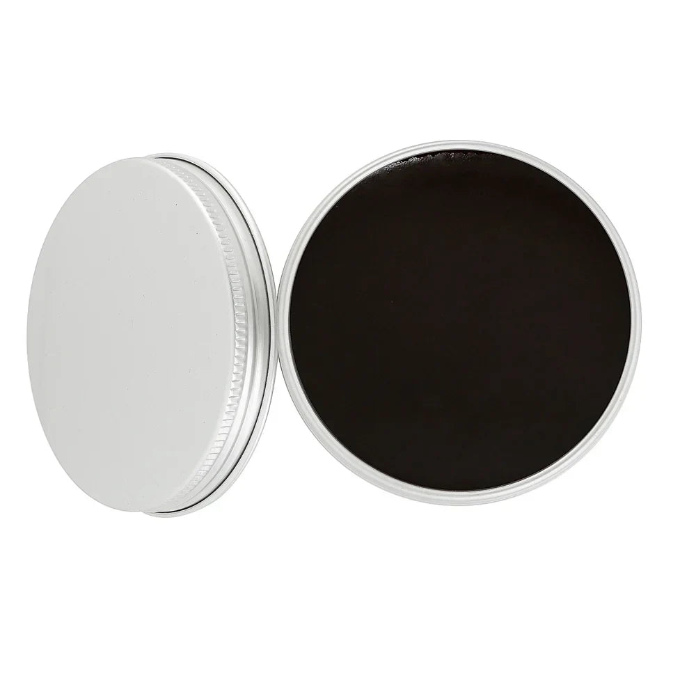 Open tin of black shoe polish with matte silver lid on white background