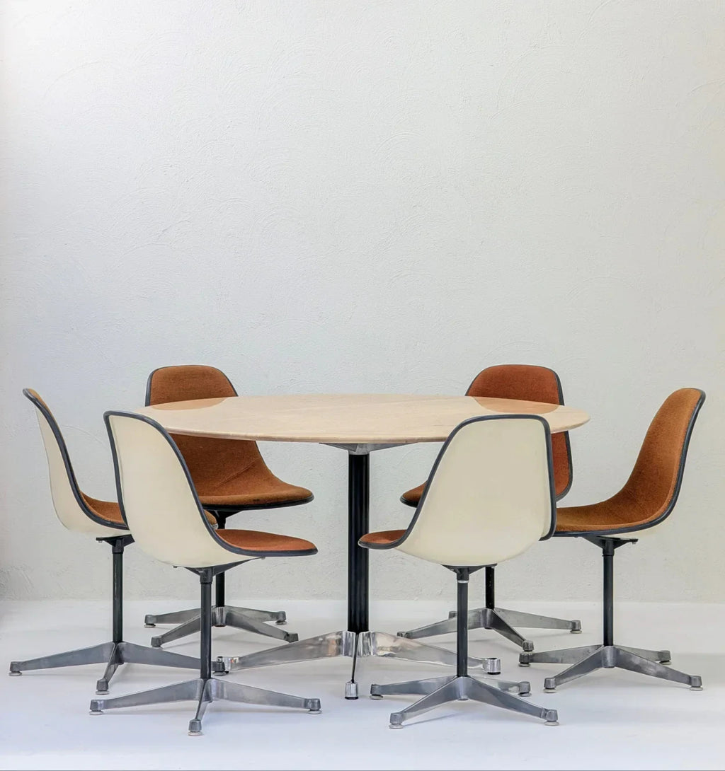 Mid-century modern round table with five brown and white swivel chairs in a minimal room
