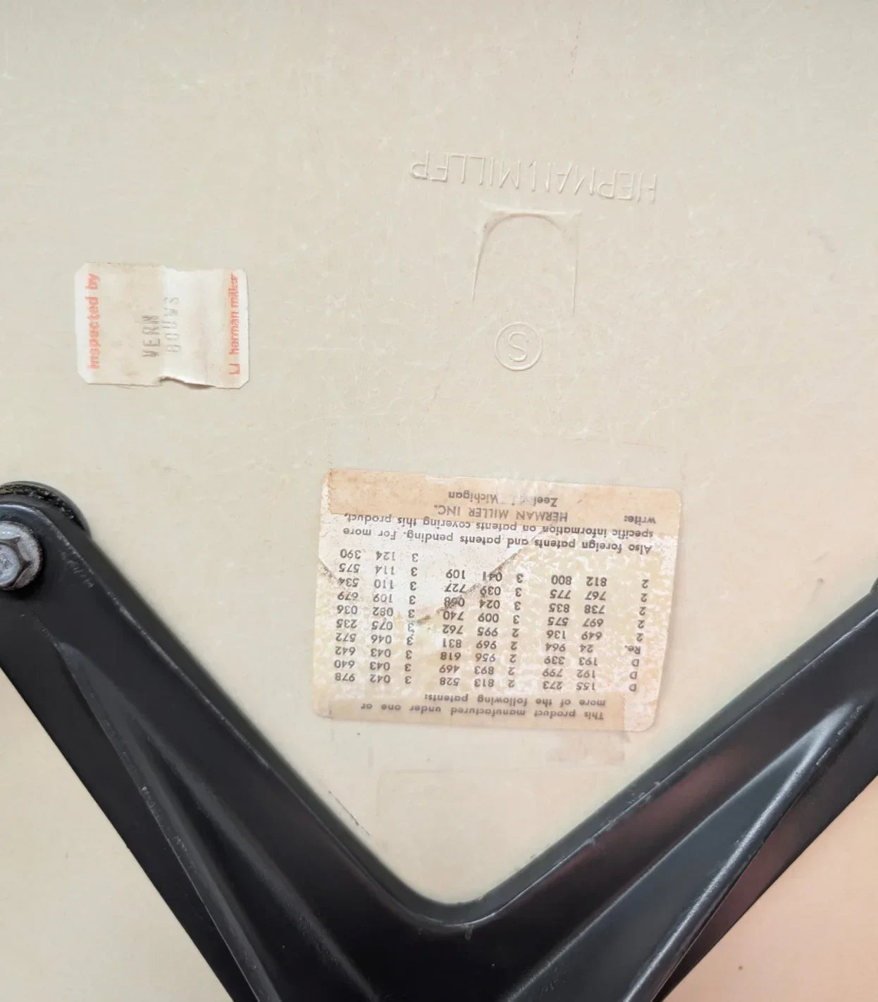Close-up of a Herman Miller chair base showing embossed logo and serial number label.