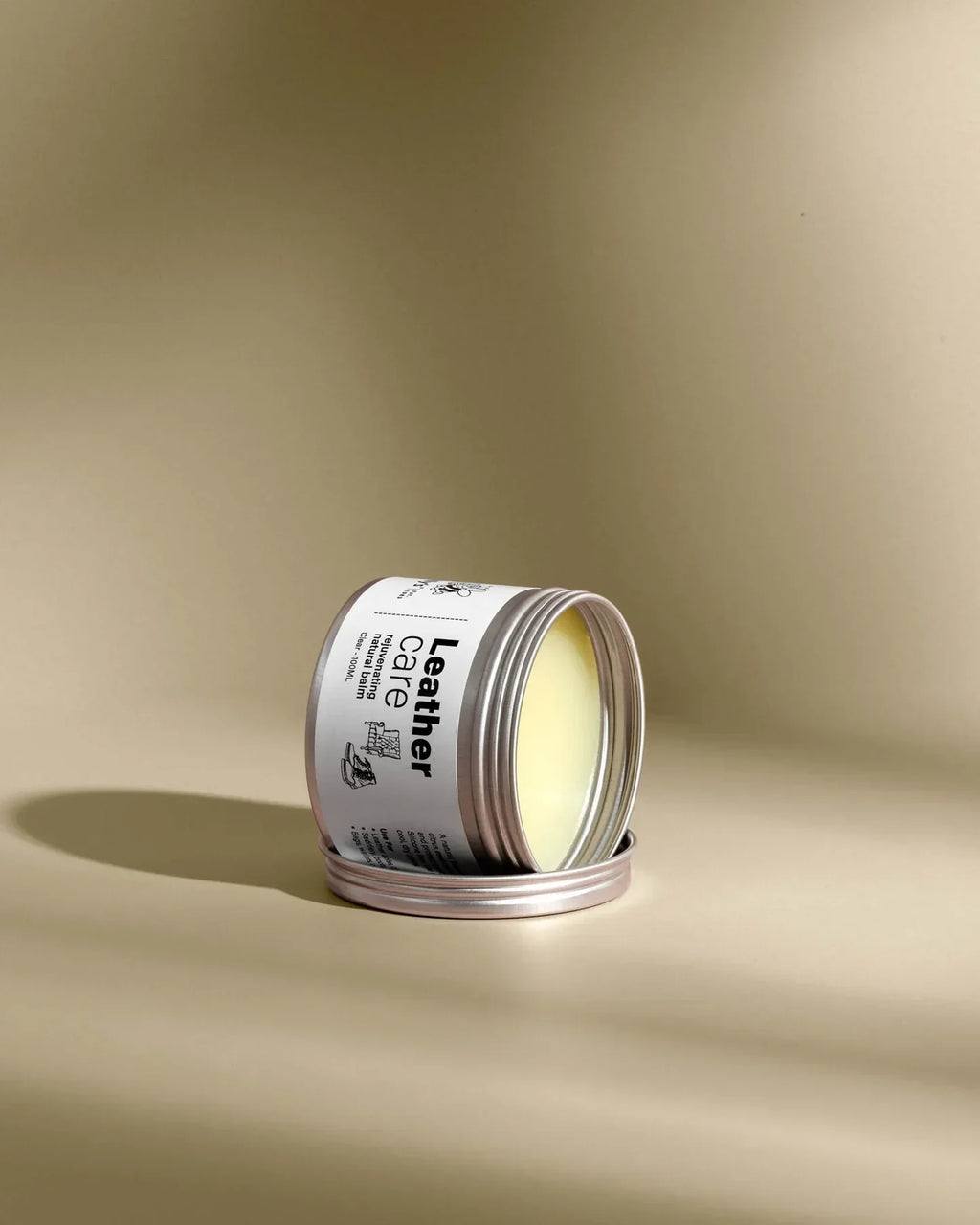 Open tin of Leather Care 100ml balm on beige background, natural leather conditioner