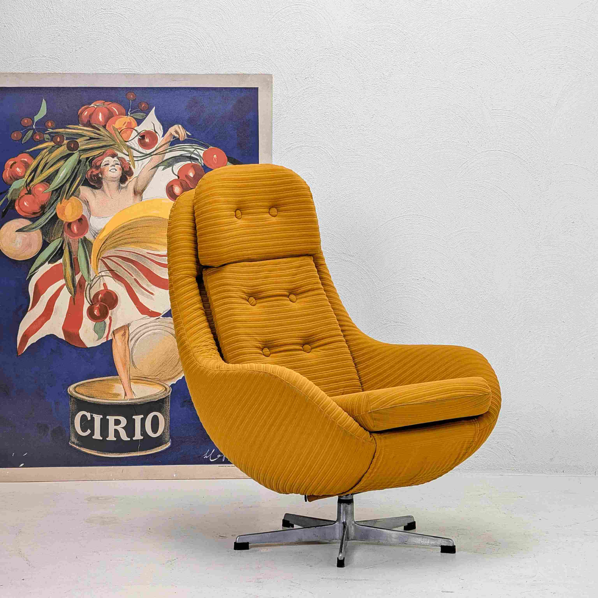 Mustard yellow armchair in front of a vintage Cirio advertisement poster.


