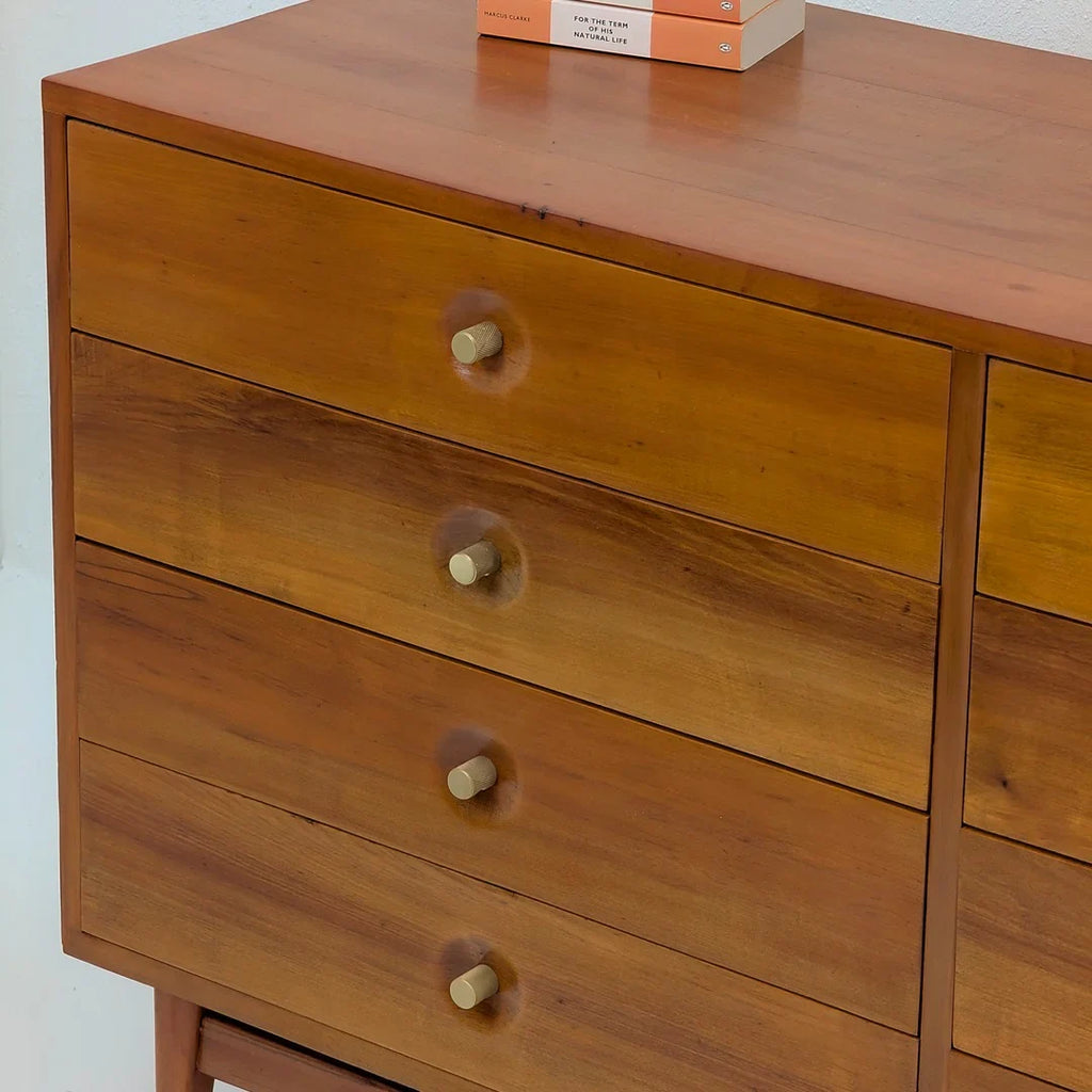 Modern wooden dresser with brass knobs and books on top, minimalist home furniture