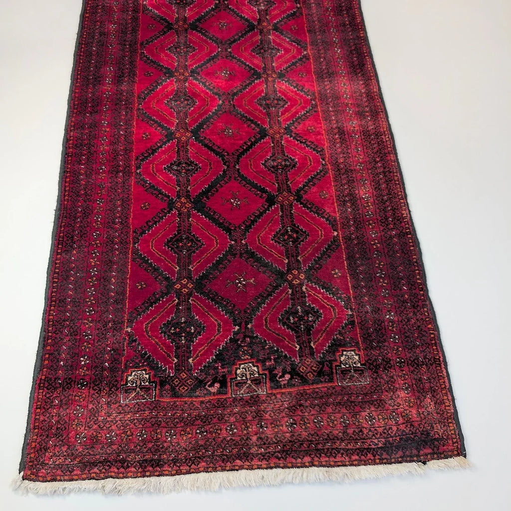 Vintage Persian rug with red geometric patterns on a white background