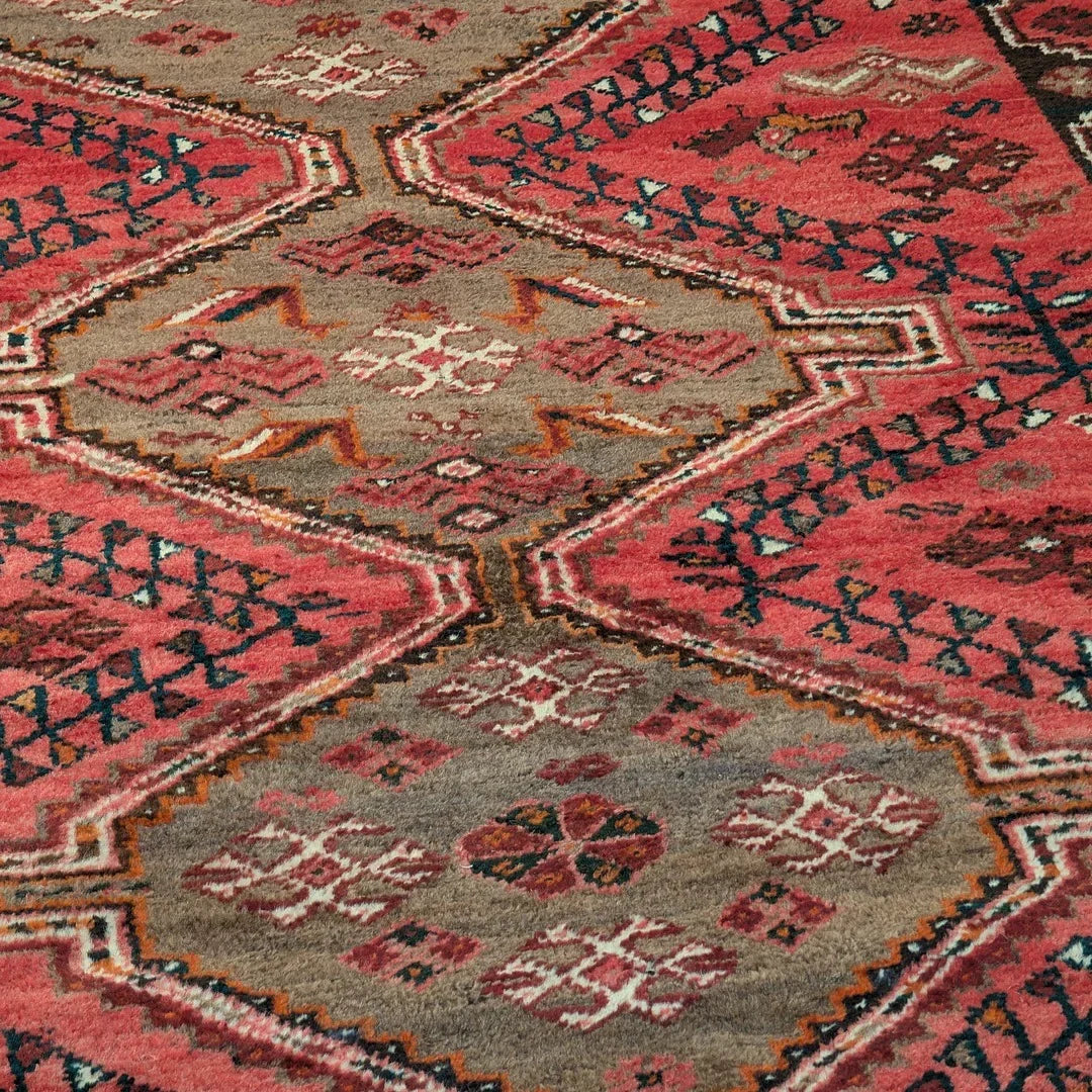 Vintage red and tan patterned area rug with geometric and tribal motifs
