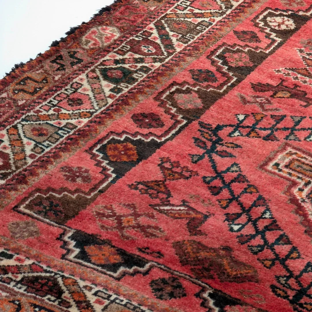 Vintage Persian rug with geometric patterns in red, brown, and cream colors