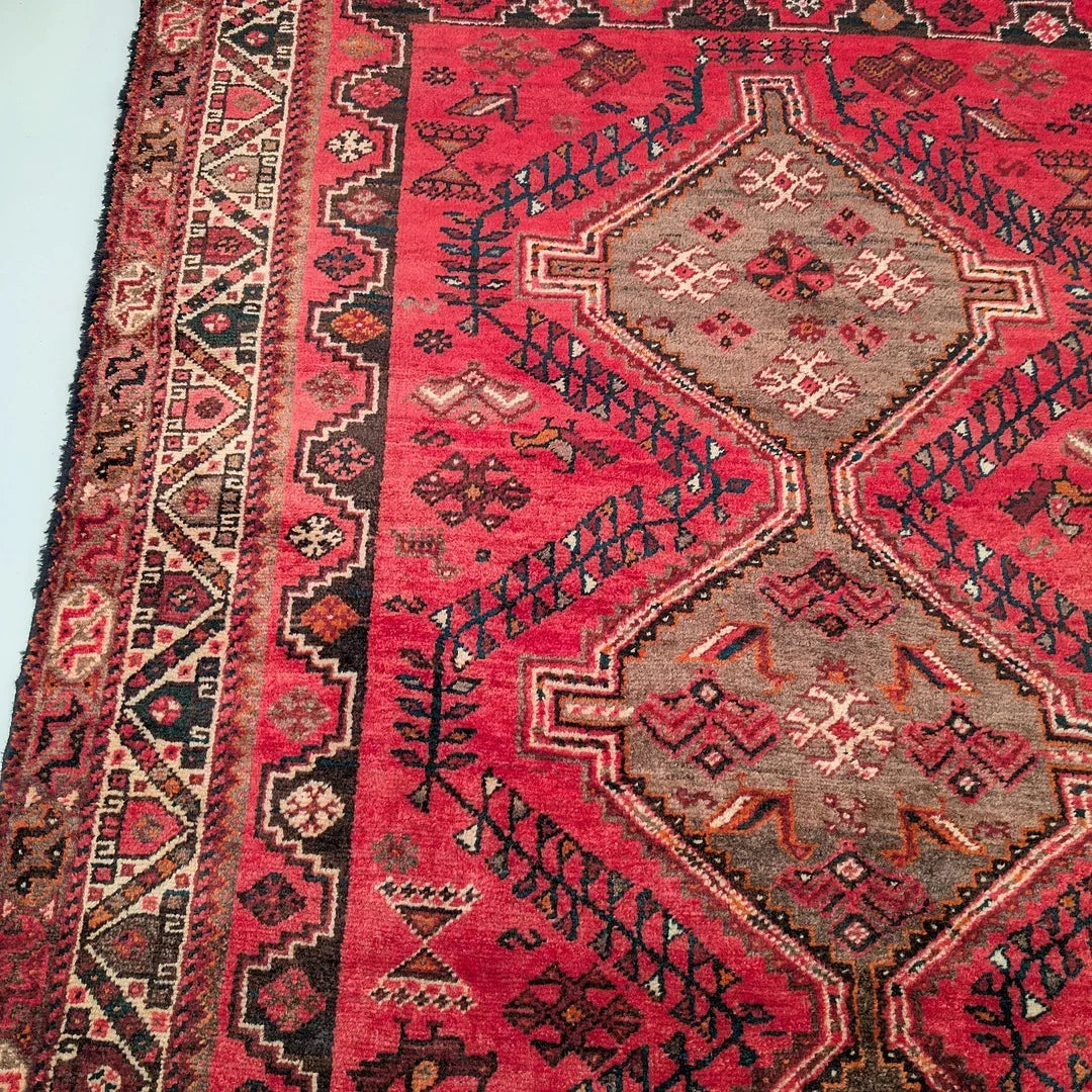 Red and beige Persian rug with geometric patterns and intricate border design
