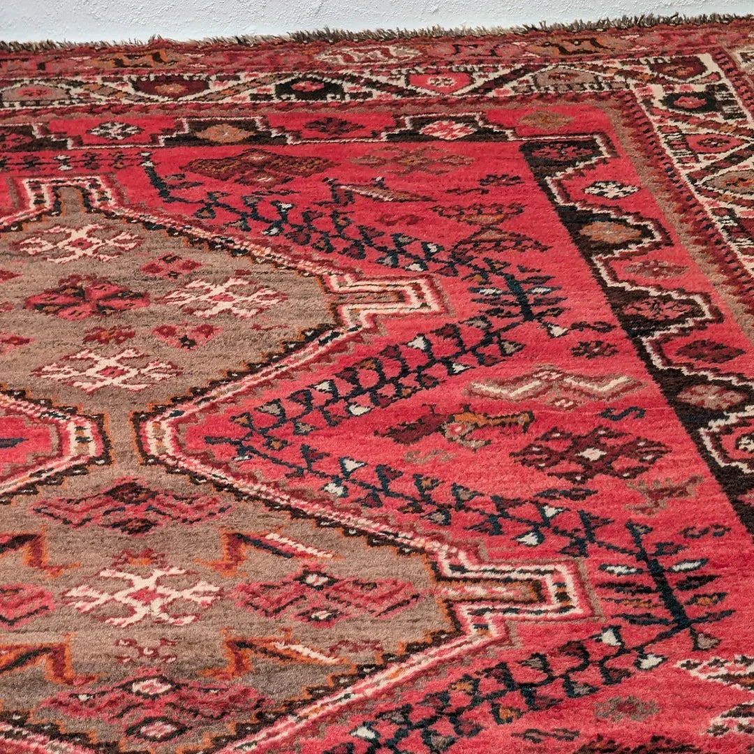 Red and beige vintage oriental rug with geometric patterns on a floor