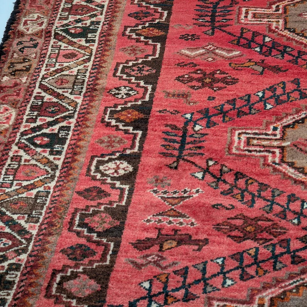 Vintage Persian rug with geometric patterns in red, brown, and cream tones