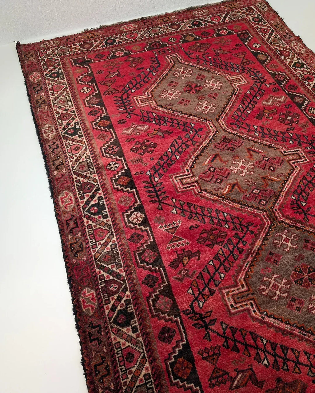 Vintage Persian red area rug with geometric and tribal patterns on a light background