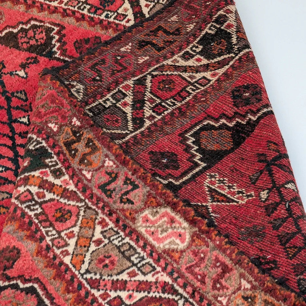 Red Persian rug with geometric patterns and intricate traditional designs, close-up view