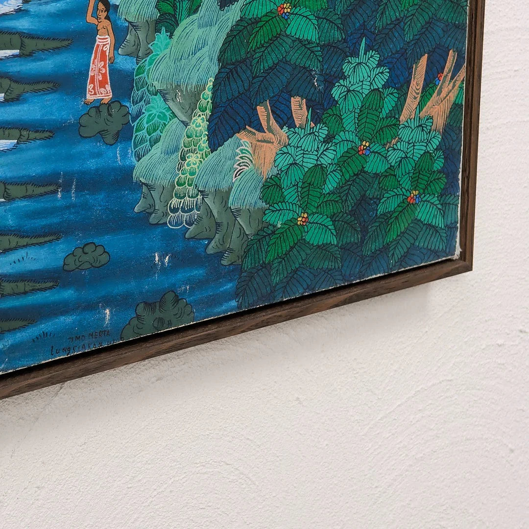 Framed artwork showing a person in red wrap by blue water and lush green tropical foliage