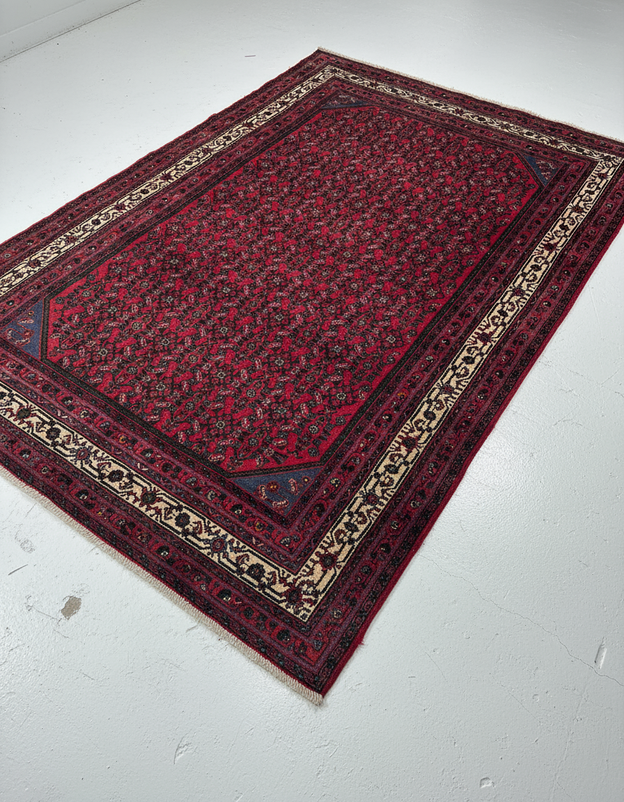 Vintage red Persian-style rug with intricate floral and geometric patterns on white floor