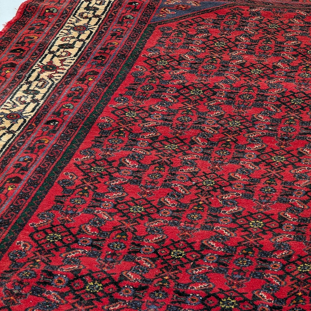 Close-up of a vintage red Persian-style rug with intricate geometric and floral patterns