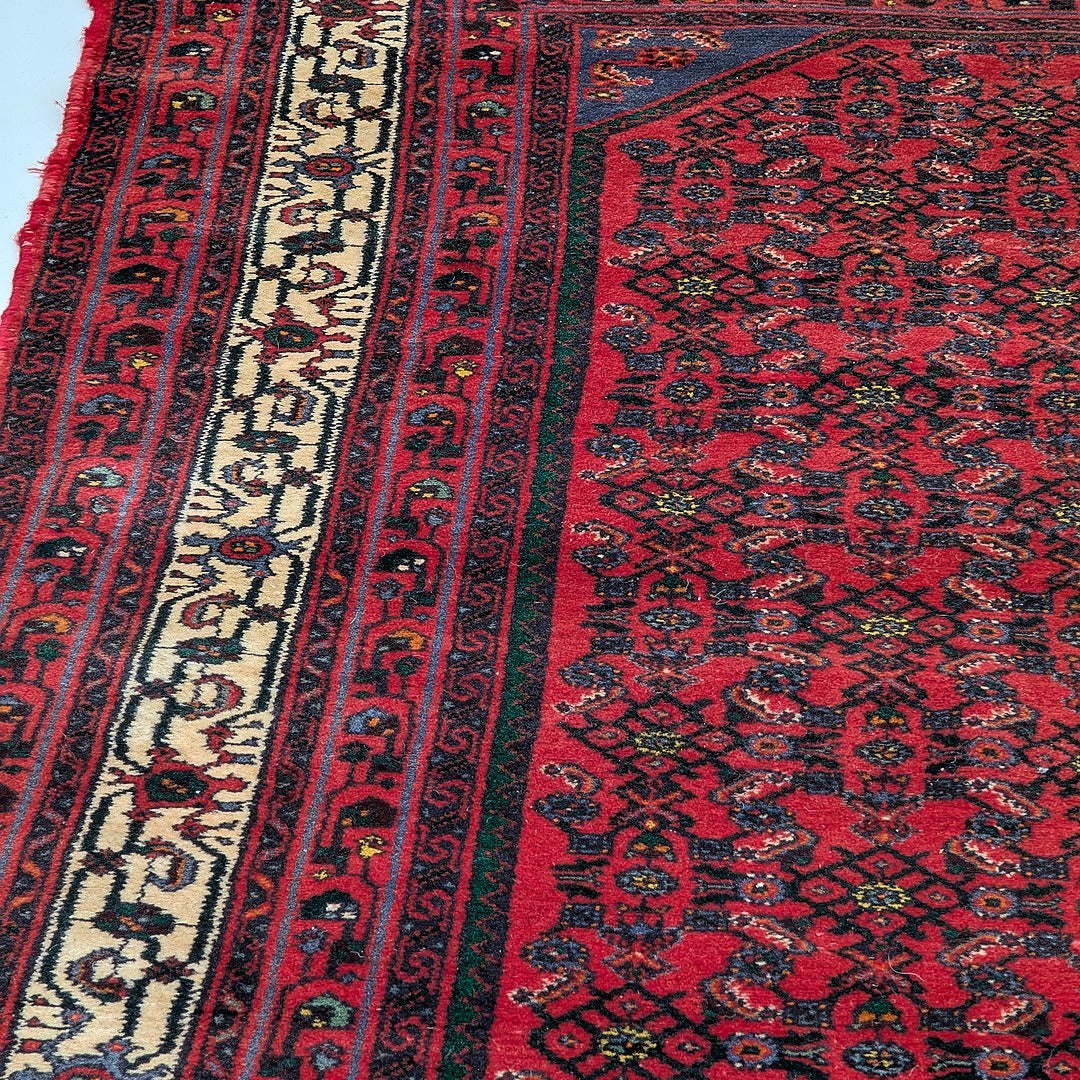 Close-up of a vibrant red Persian-style kilim rug with intricate geometric and floral patterns