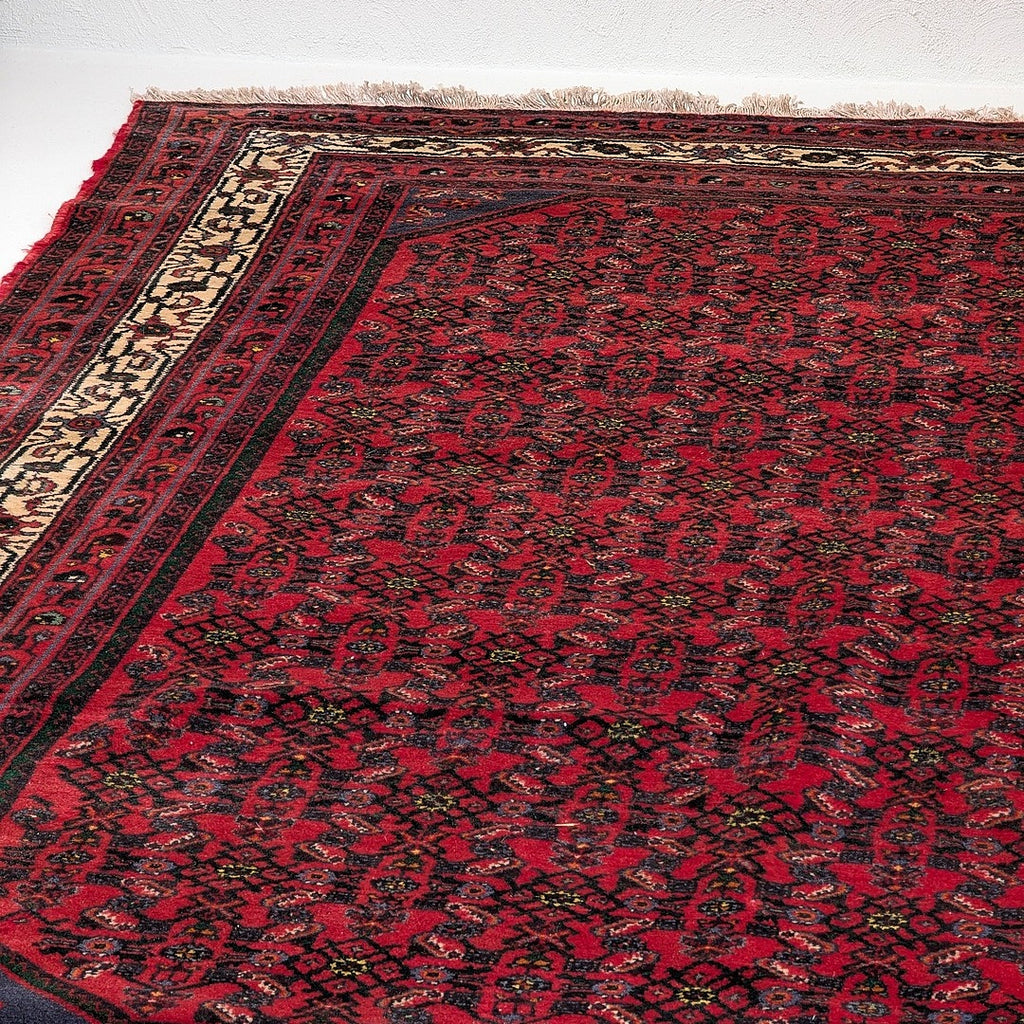 Vintage red kilim rug with intricate dark floral patterns and beige border fringe