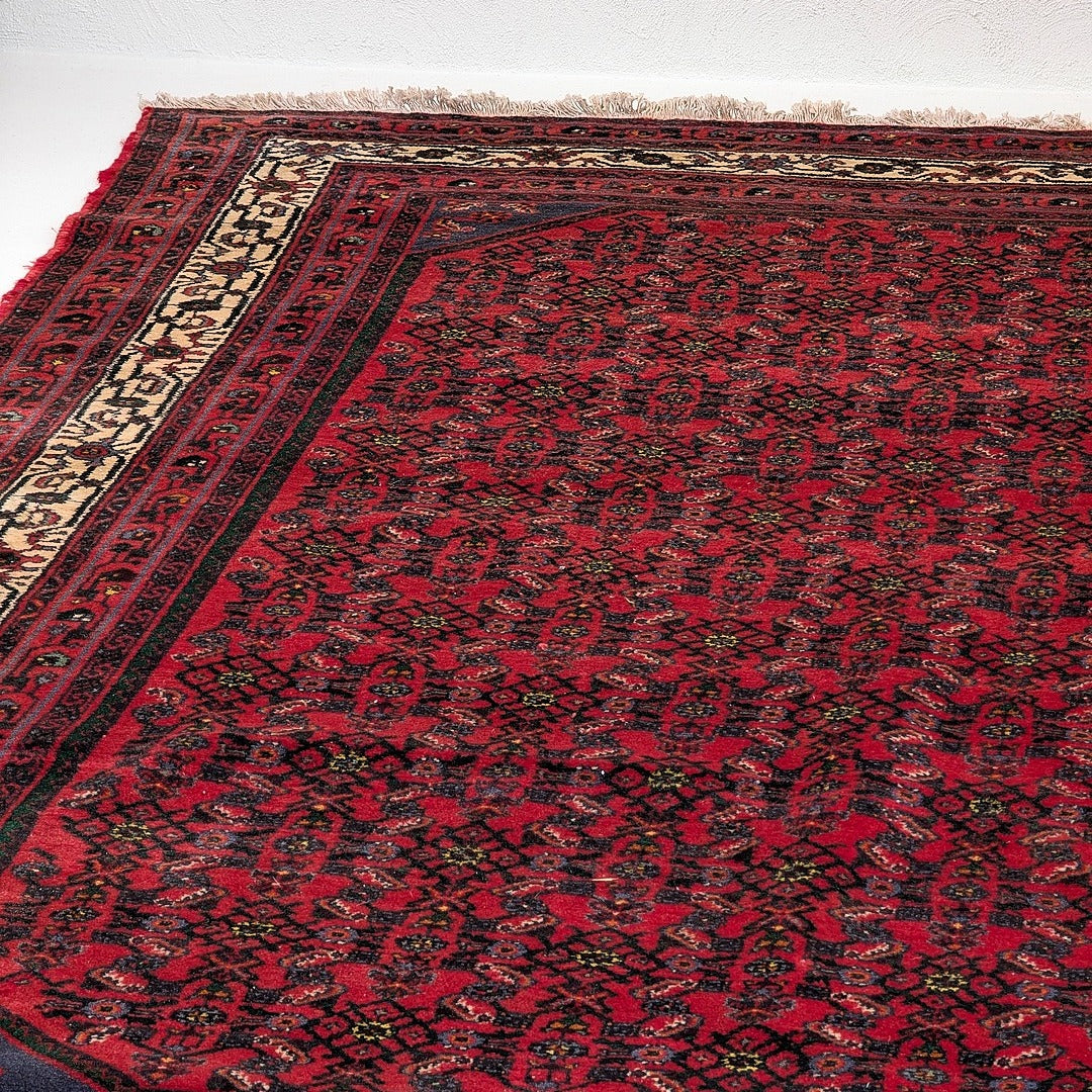 Vintage red kilim rug with intricate dark floral patterns and beige border fringe