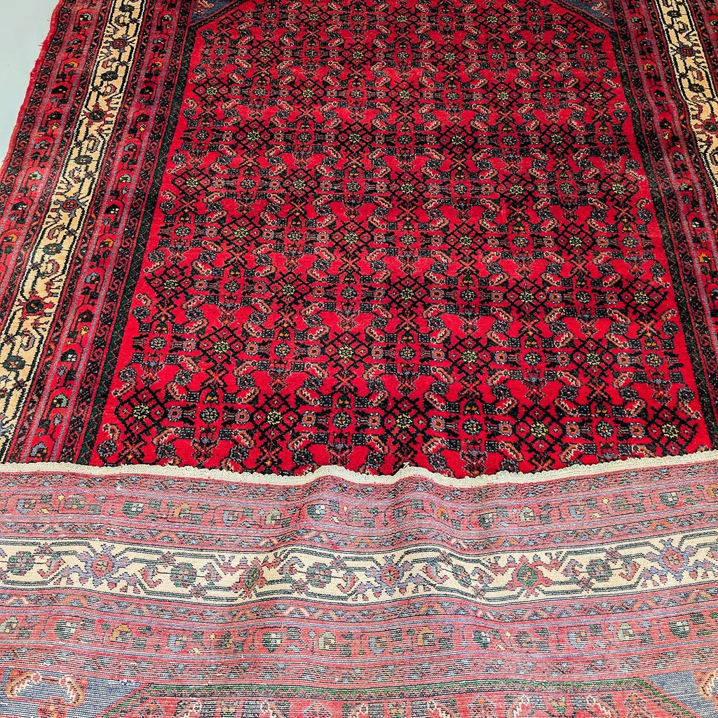 Detailed close-up of vintage red patterned rug with black and beige floral borders