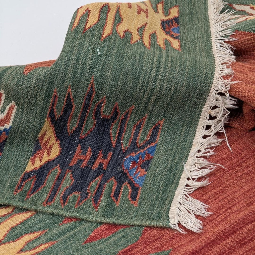 Close-up of colorful woven kilim rug with geometric patterns and fringed edge