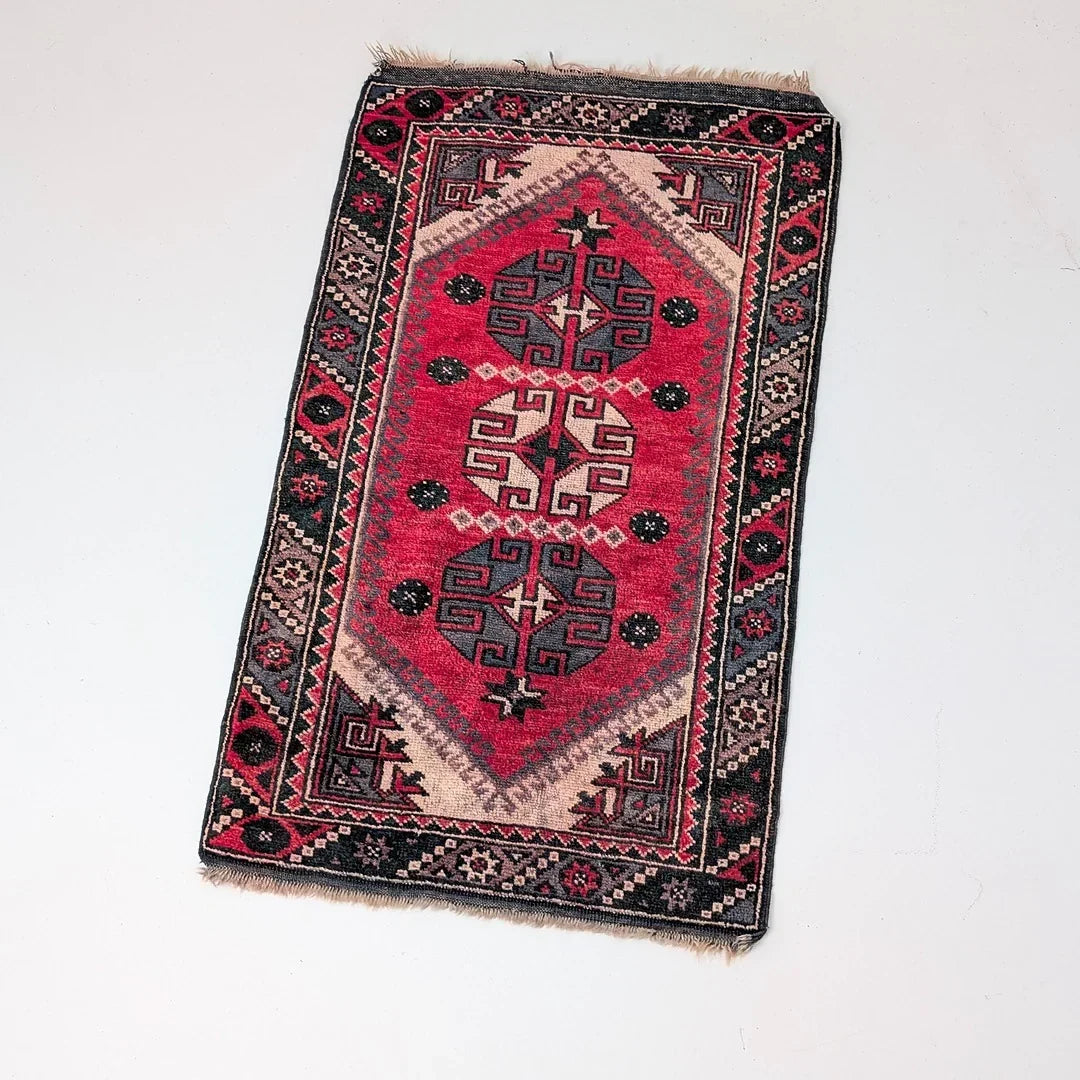 Handmade red and black Turkish rug with geometric tribal patterns on a white background