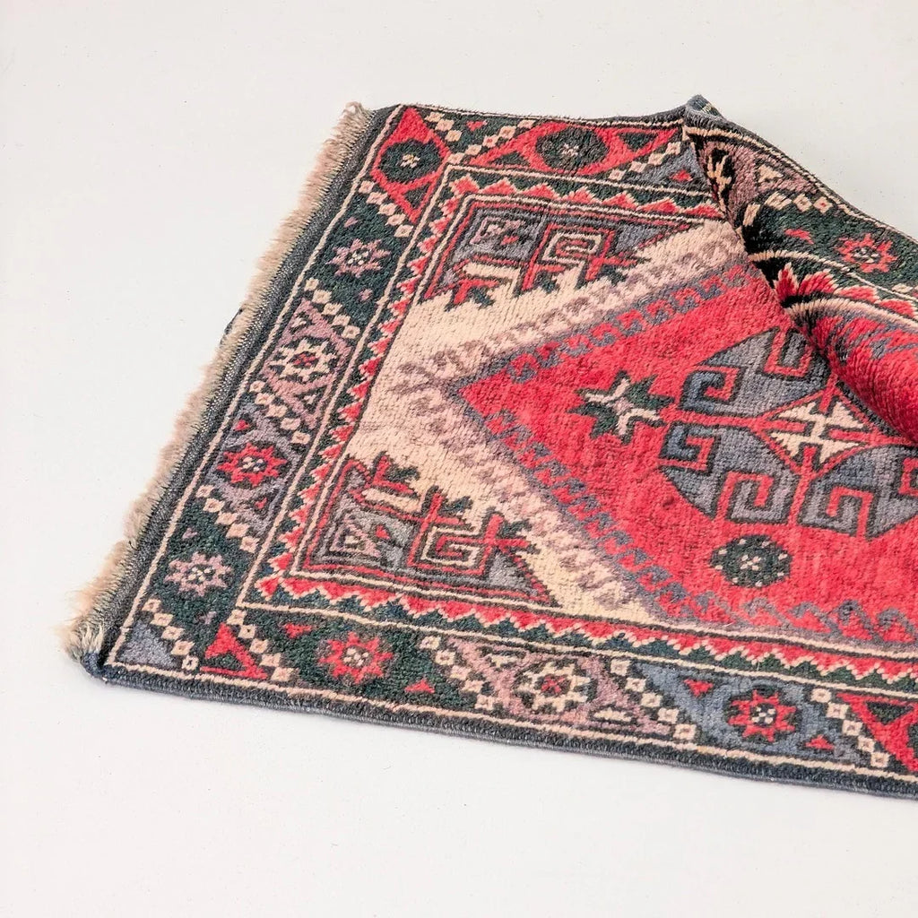 Patterned red and black geometric area rug with traditional motifs on a light surface