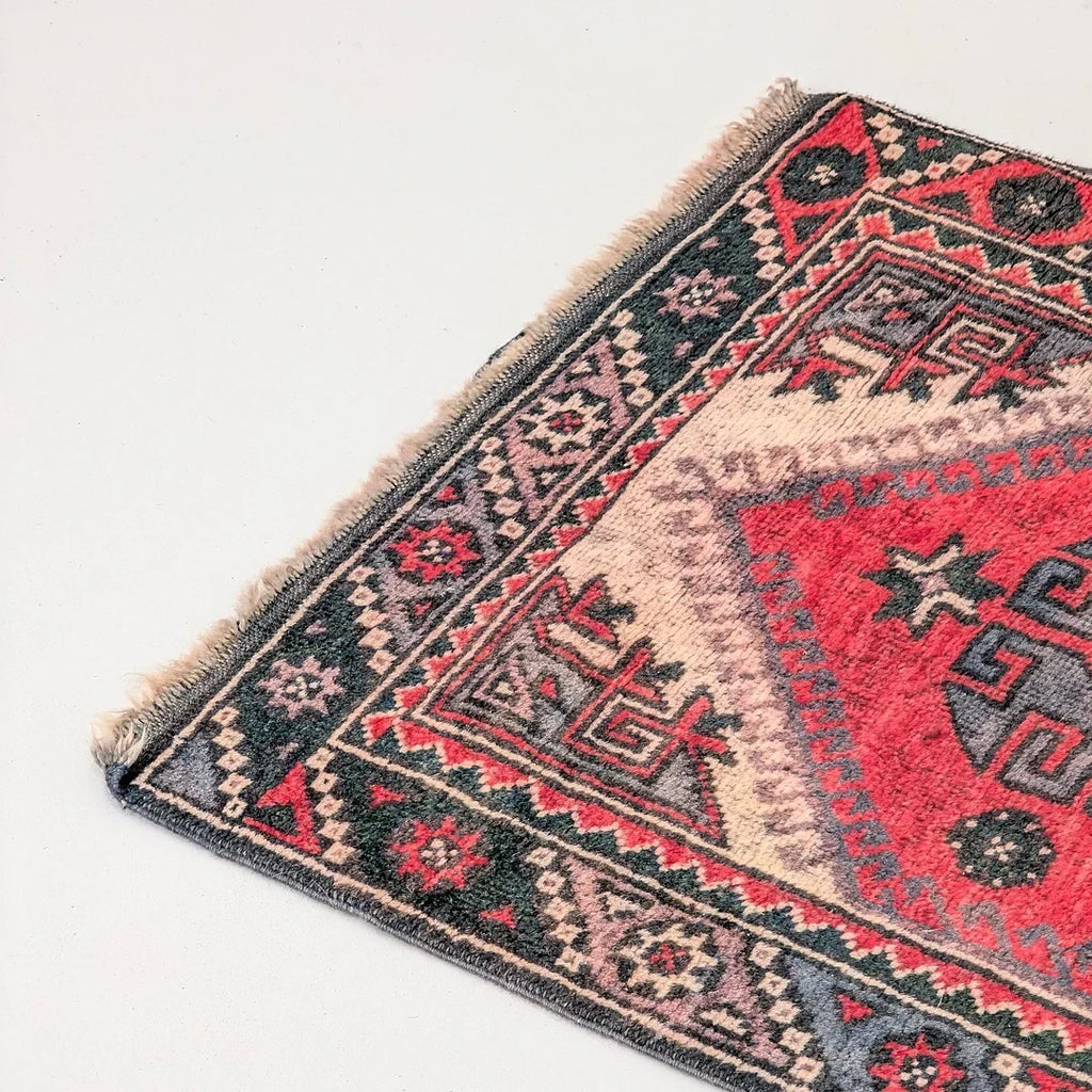 Colorful geometric patterned corner of a vintage Turkish rug on a light background