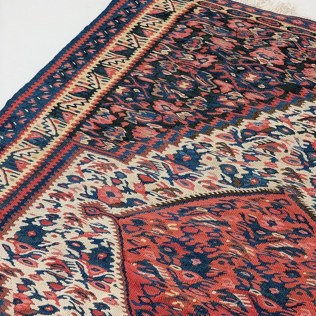 Close-up of a traditional Persian rug with red, navy blue, and cream floral patterns