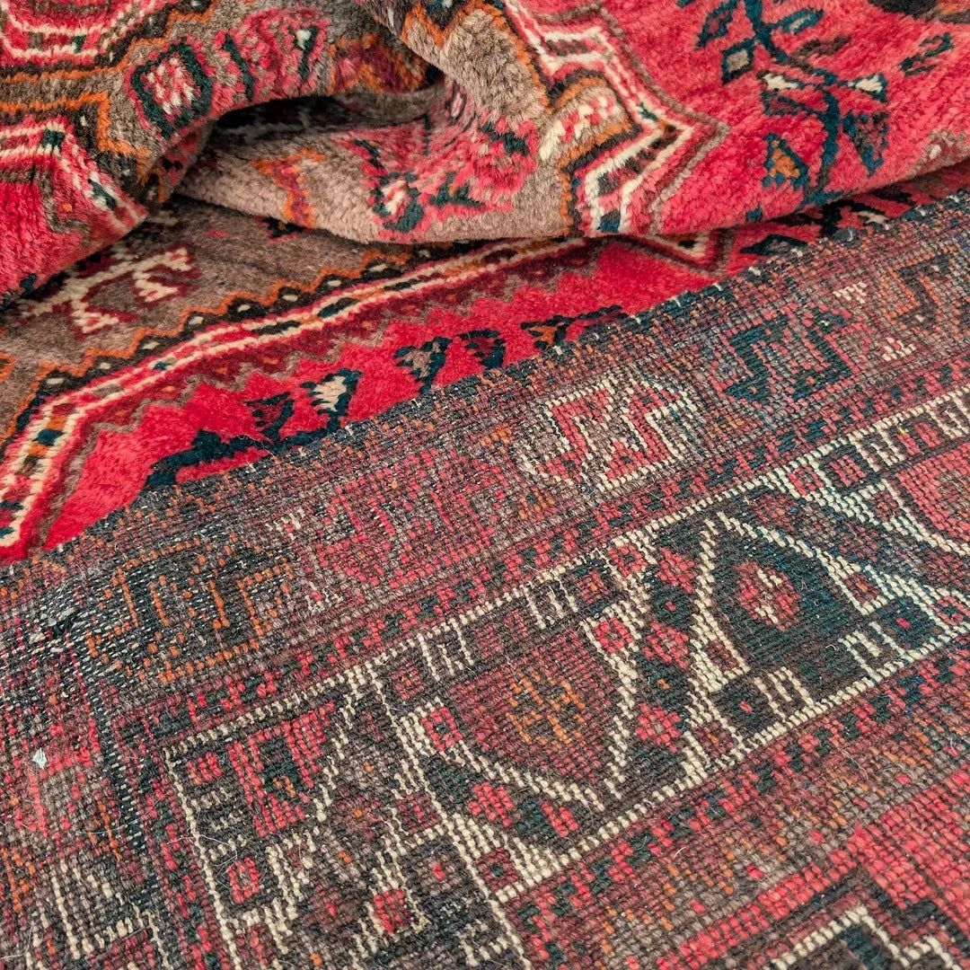 Close-up of a colorful vintage Persian rug with geometric patterns and red, blue, and brown tones