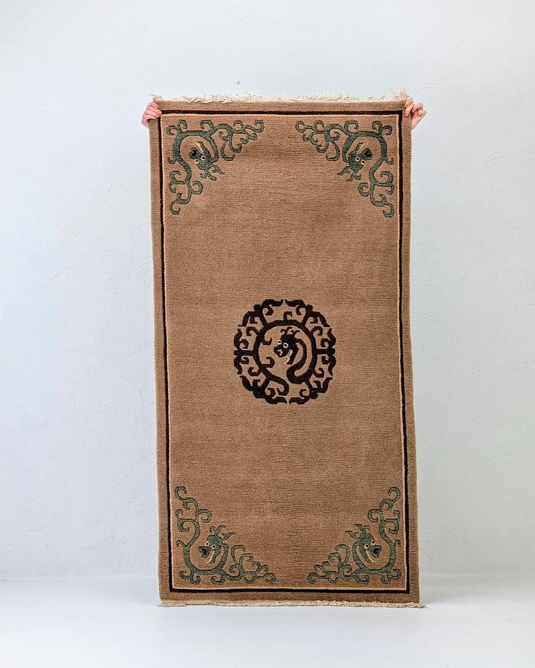 Person holding a tan rug with decorated dragon motifs and a round central medallion