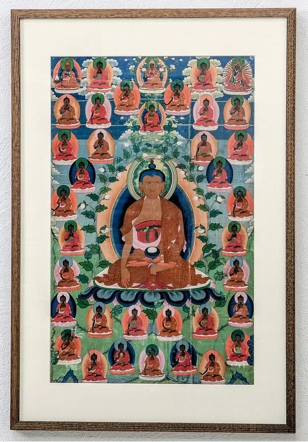 Framed Tibetan thangka painting with central seated Buddha surrounded by smaller Buddhas