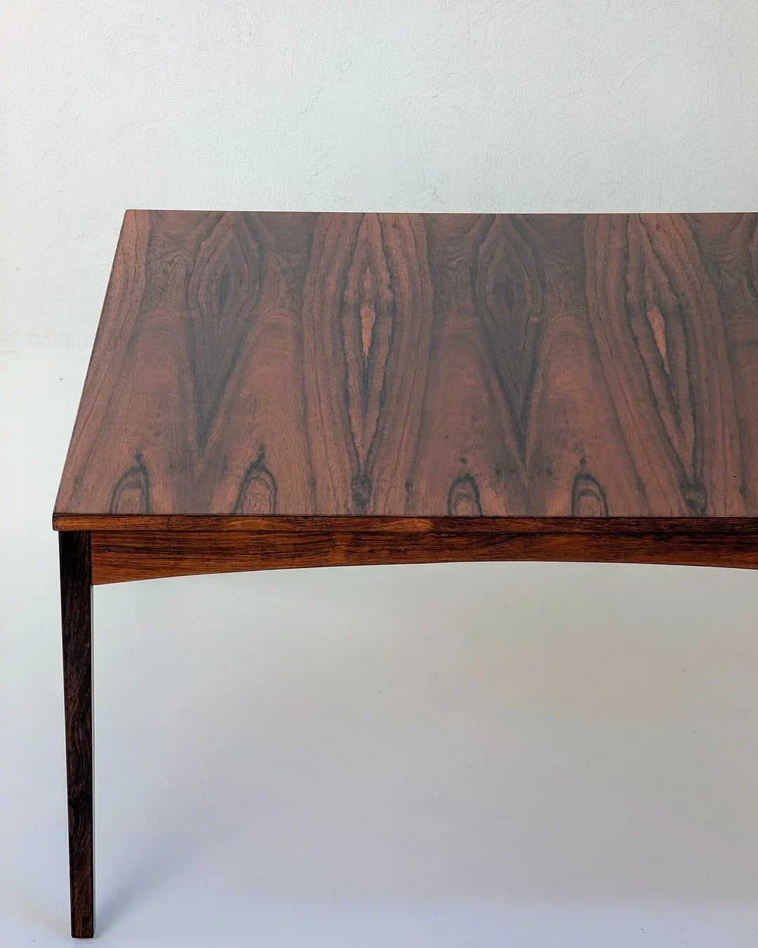 Mid-century modern rosewood dining table with distinctive wood grain pattern on light background