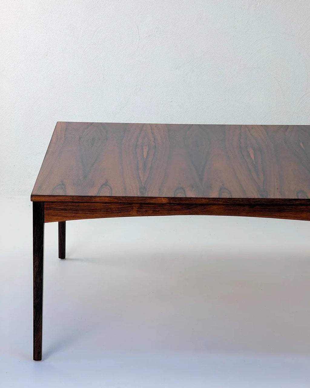 Mid-century modern rosewood coffee table with rich wood grain on white background