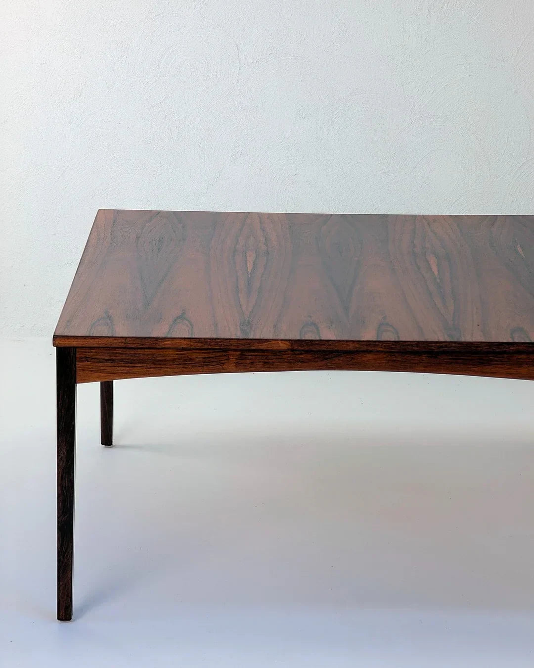 Mid-century modern rosewood coffee table with rich wood grain on white background