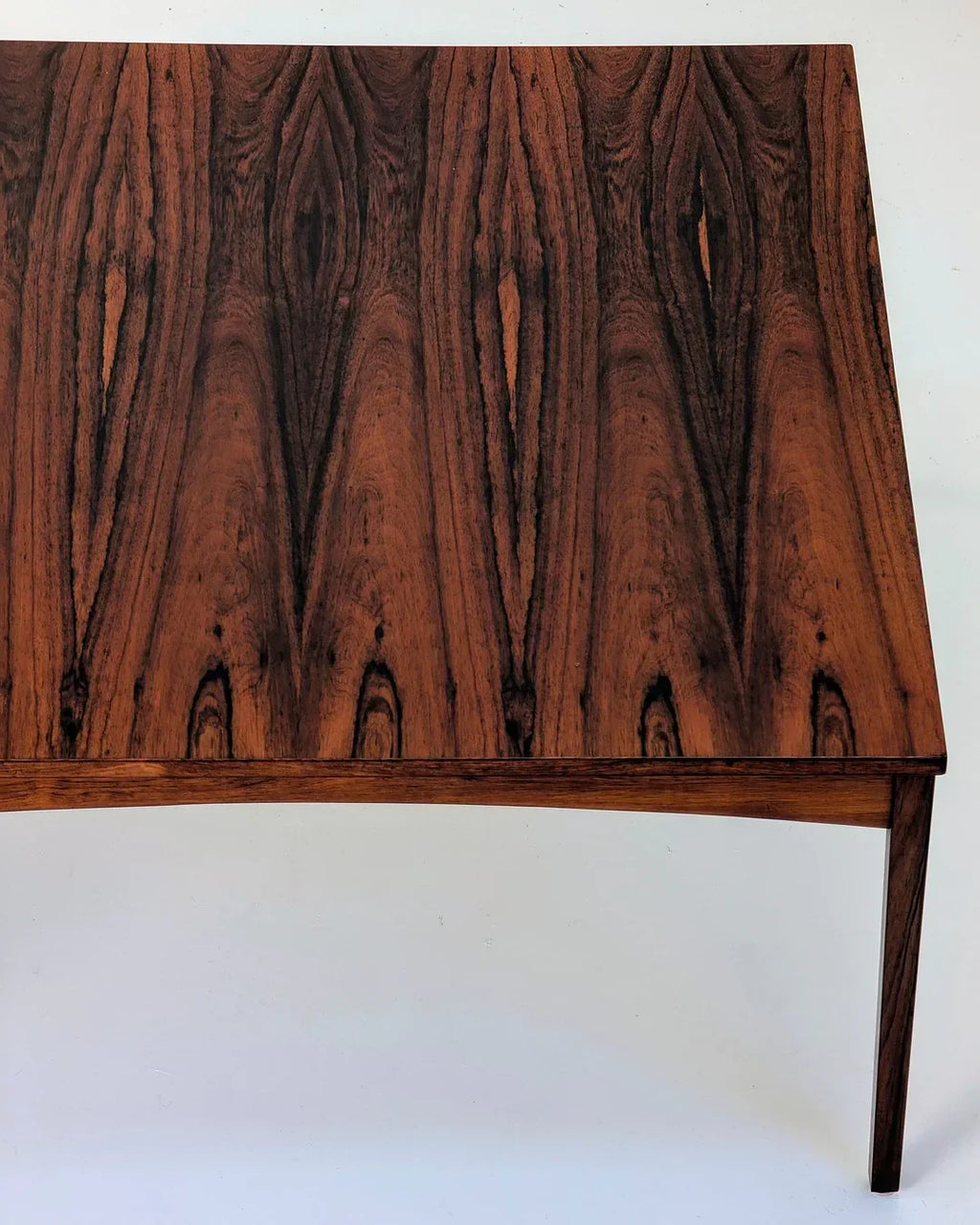 Mid-century modern rosewood dining table with rich wood grain pattern and tapered legs