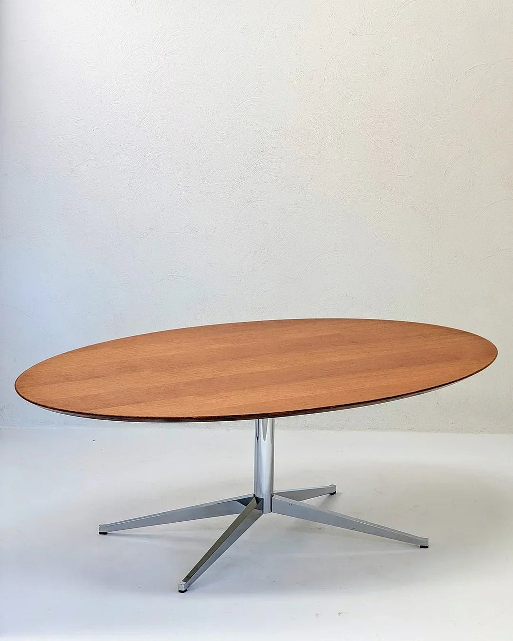 Oval wood coffee table with chrome metal base on white background