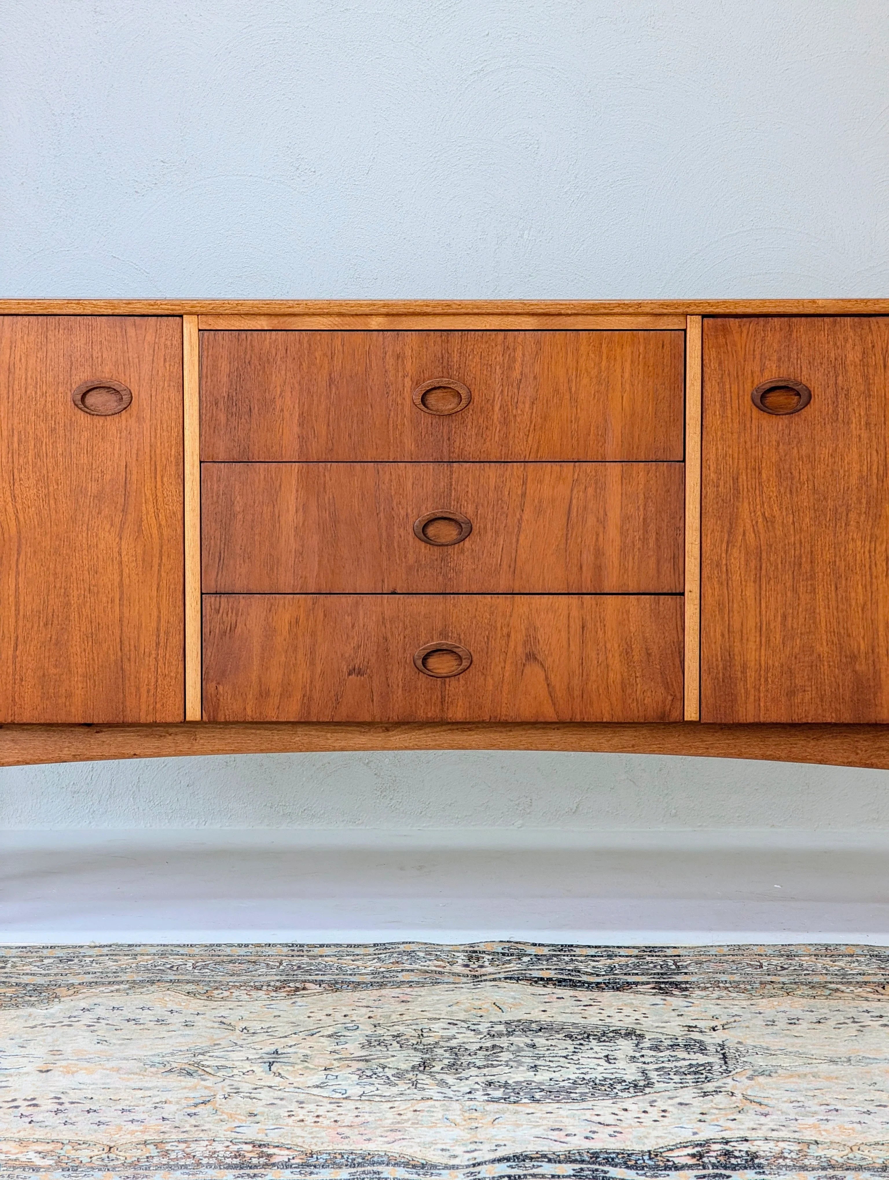 Mid-century modern wooden sideboard with three drawers and two cabinets on a patterned rug