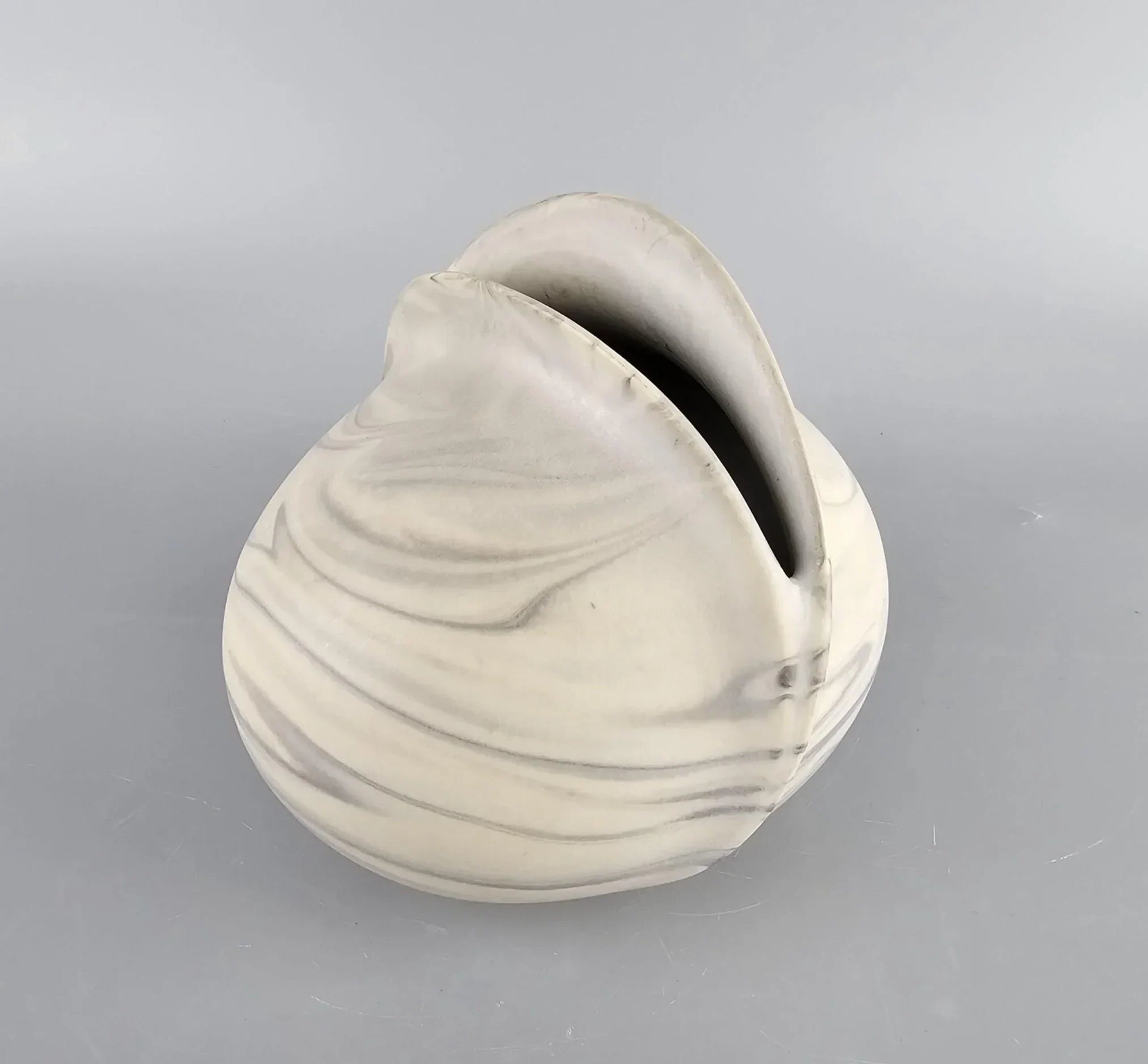 Modern marbled ceramic vase with a sculptural, abstract design on a gray background