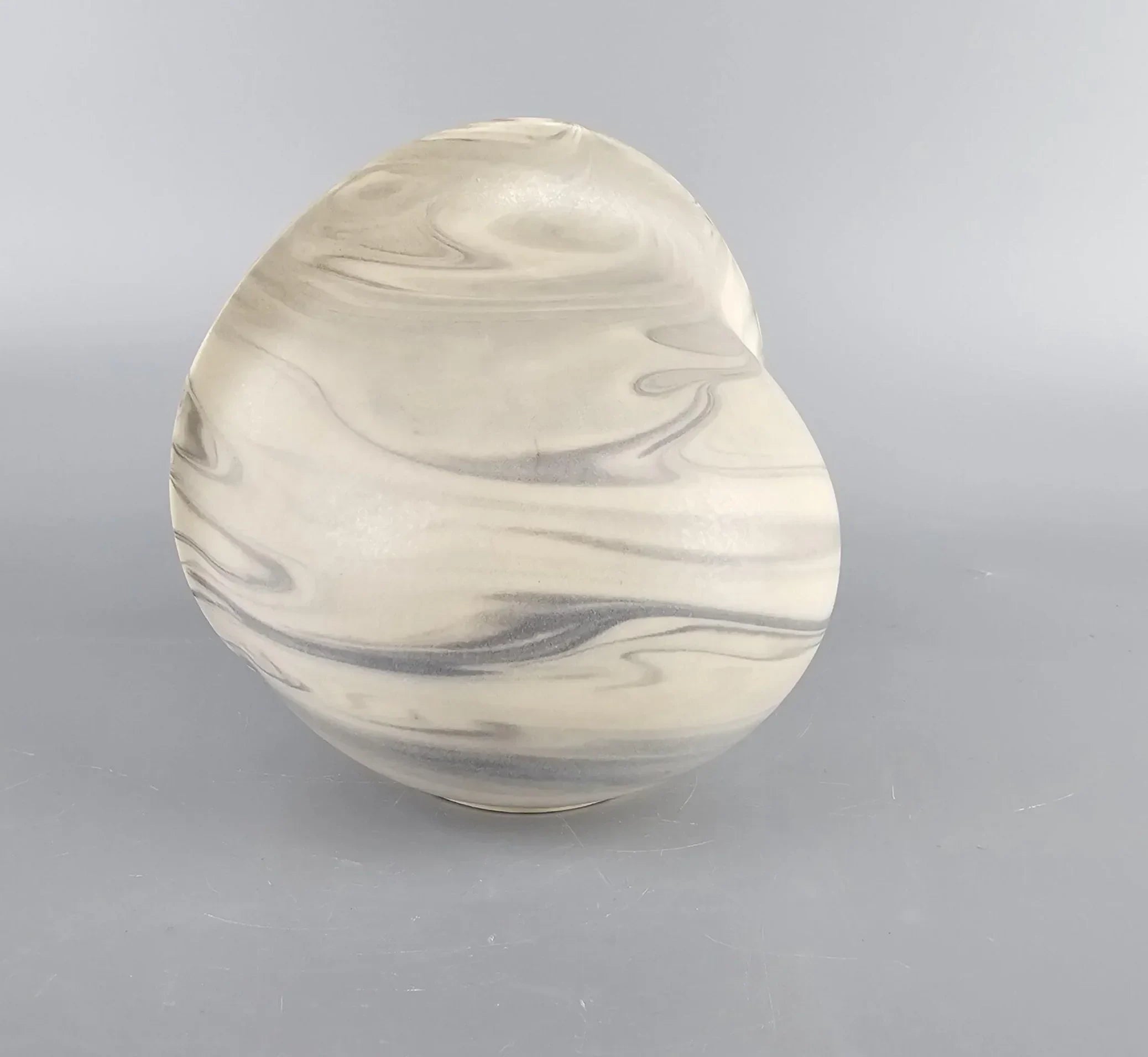 Round marbled ceramic vase with gray and cream swirl pattern on a plain gray background