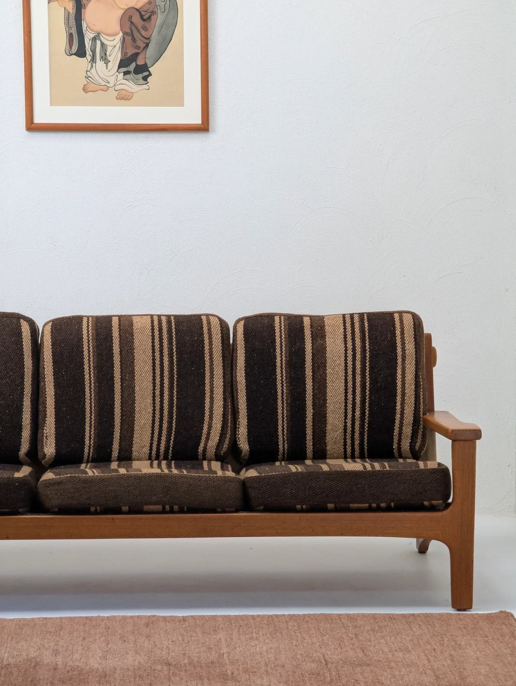 Vintage striped brown sofa with wooden frame, wall art, and beige rug in minimalist room