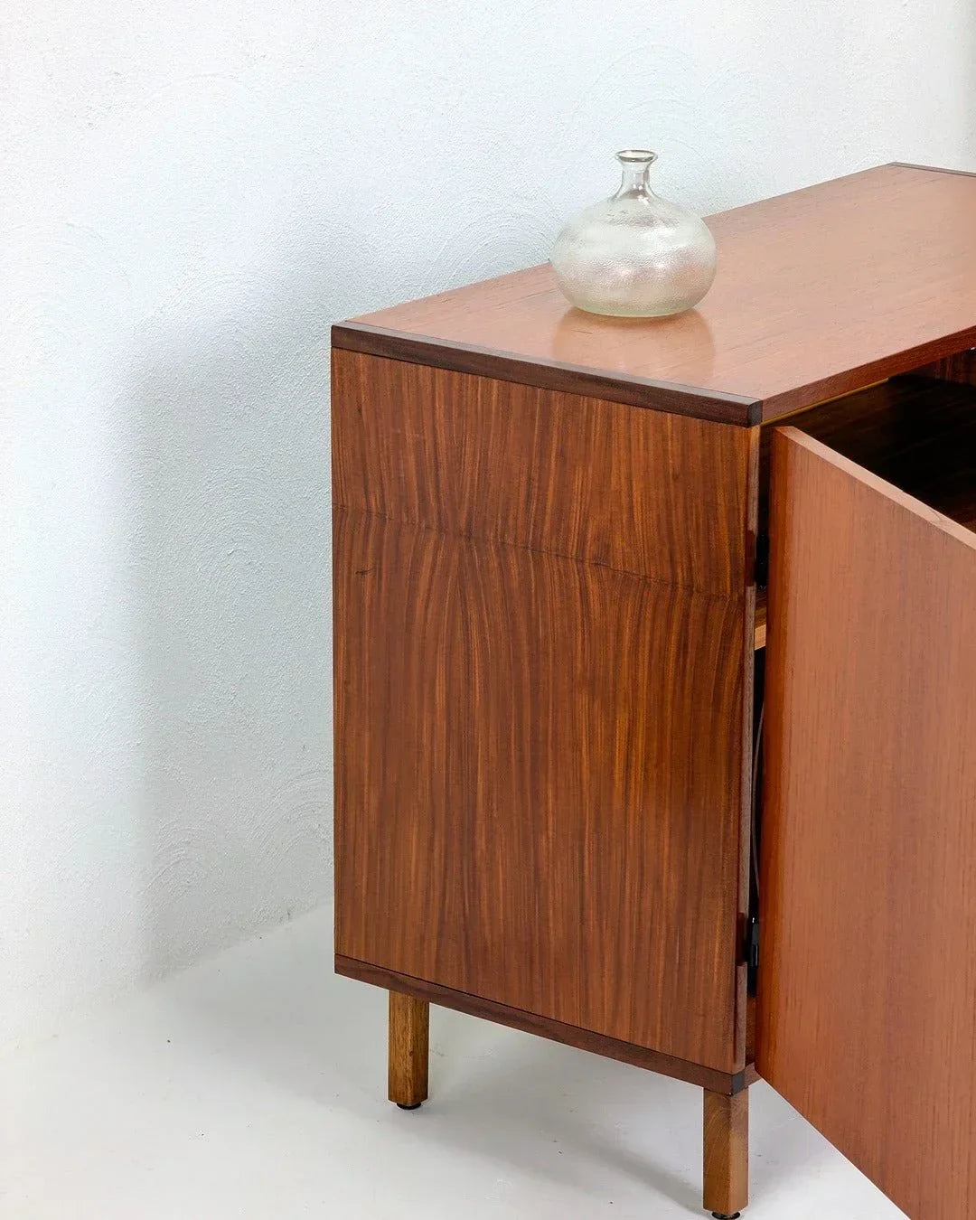 Danish teak LP vinyl cabinet from the 1970s with glass vase on top against white wall